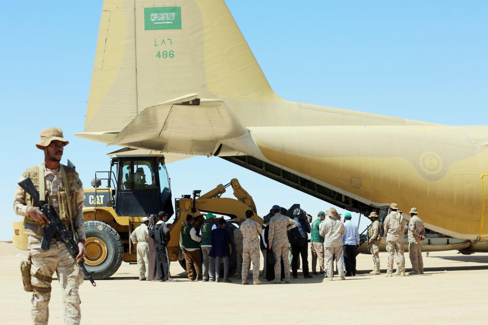 Saudi soldiers stand guard as workers unload aid from a Saudi air force cargo plane at an airfield in Yemen's central province of Marib, on February 8, 2018. / AFP / ABDULLAH AL-QADRY
