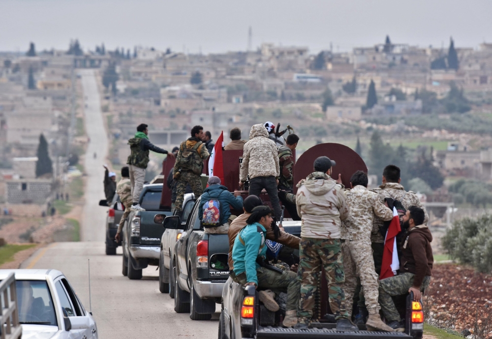 A picture taken on February 20, 2018 shows a convoy of pro-Syrian government fighters arriving in Syria's northern region of Afrin. Kurdish forces said in a statement on February 20 that pro-regime fighters deployed to Syria's Afrin region will take up positions and «participate in defending the territorial unity of Syria and its borders», countering Turkey's offensive on the area. / AFP / George OURFALIAN
