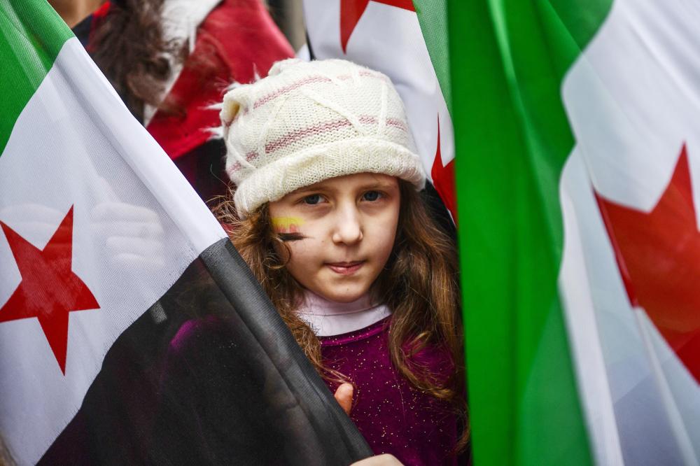 A girl holds a Syrian former independence flag (which have been adopted by forces fighting against Syrian pro-government forces in Syria) in front of Russian Consulate in Istanbul on February 22, 2018 during a protest against the airstrikes and shelling by the Syrian government forces in Ghouta. The Syrian regime rained rockets and bombs on Eastern Ghouta on February 22, killing another 19 civilians as international pressure mounted to stop the carnage in the rebel-held enclave. / AFP / OZAN KOSE
