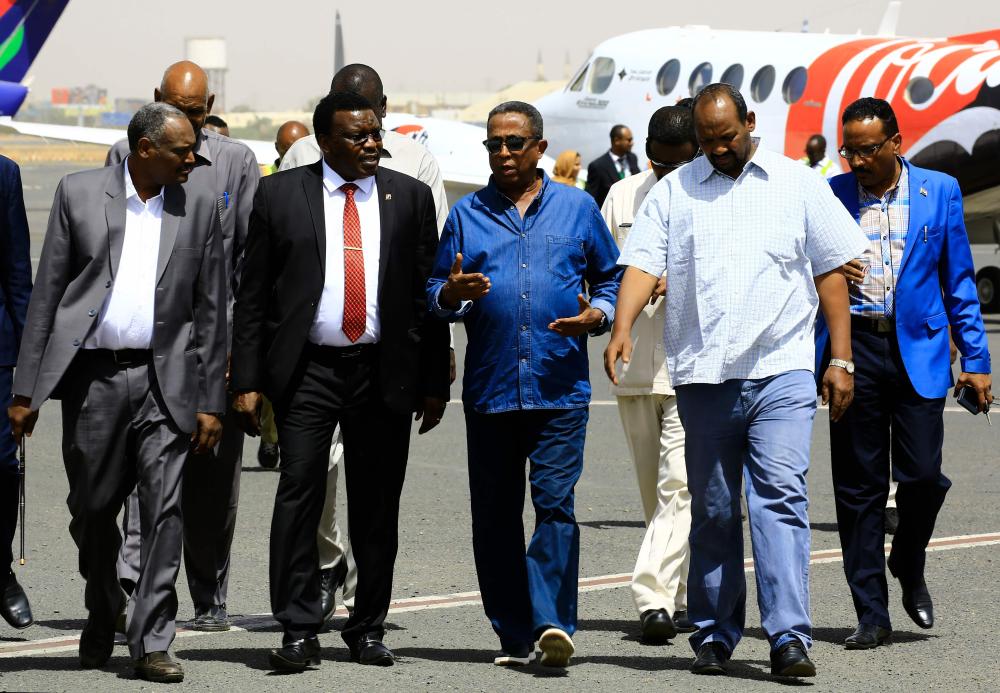 Sudanese Minister of Youth and Sports Abdul Karim Mussa (2L) talks to Osama Daoud  (3R) Chairman of DAL Group as they walk on the tarmac to see the plane carrying the FIFA World Cup Trophy following its arrival in Khartoum on February 22, 2018, as it tours the globe ahead of this summer's tournament in Russia.  / AFP / ASHRAF SHAZLY
