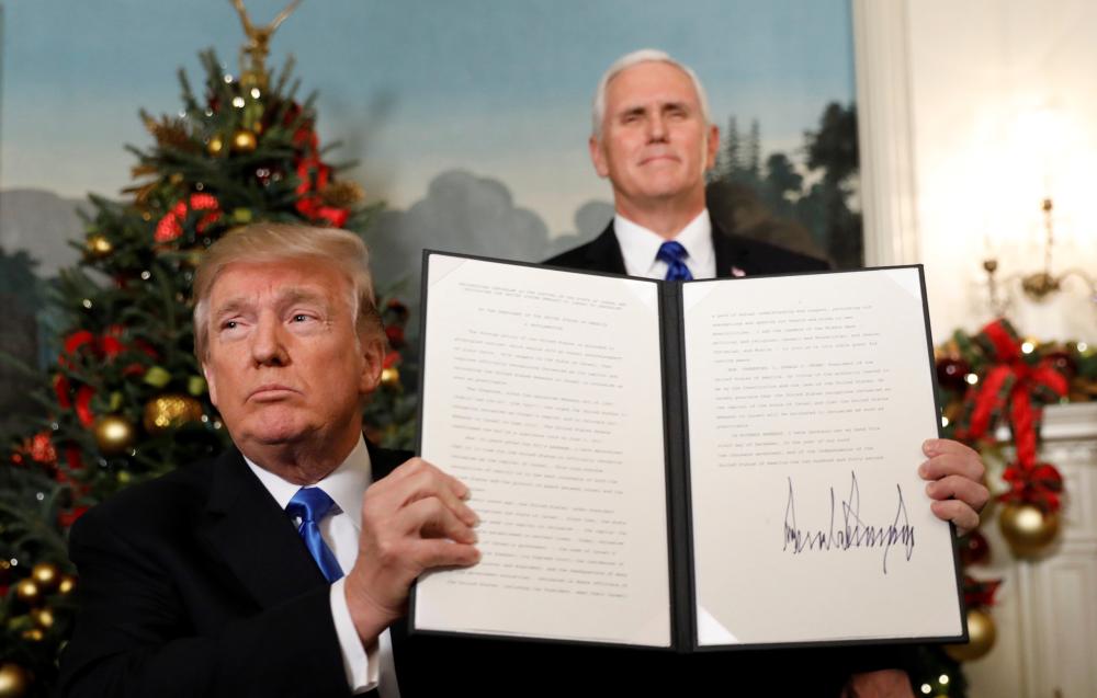 U.S. Vice President Mike Pence stands behind as U.S. President Donald Trump holds up the proclamation he signed that the United States recognizes Jerusalem as the capital of Israel and will move its embassy there, during an address from the White House in Washington, U.S., December 6, 2017.  REUTERS/Kevin Lamarque