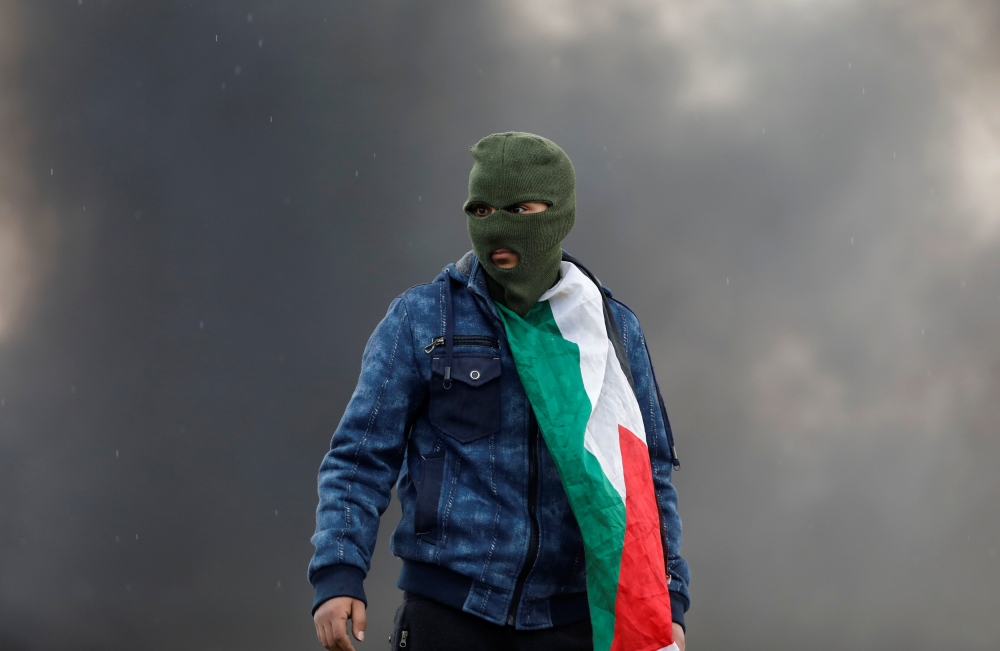 A Palestinian demonstrator takes up position during clashes with Israeli troops near Nablus, in the occupied West Bank February 23, 2018. REUTERS/Mohamad Torokman