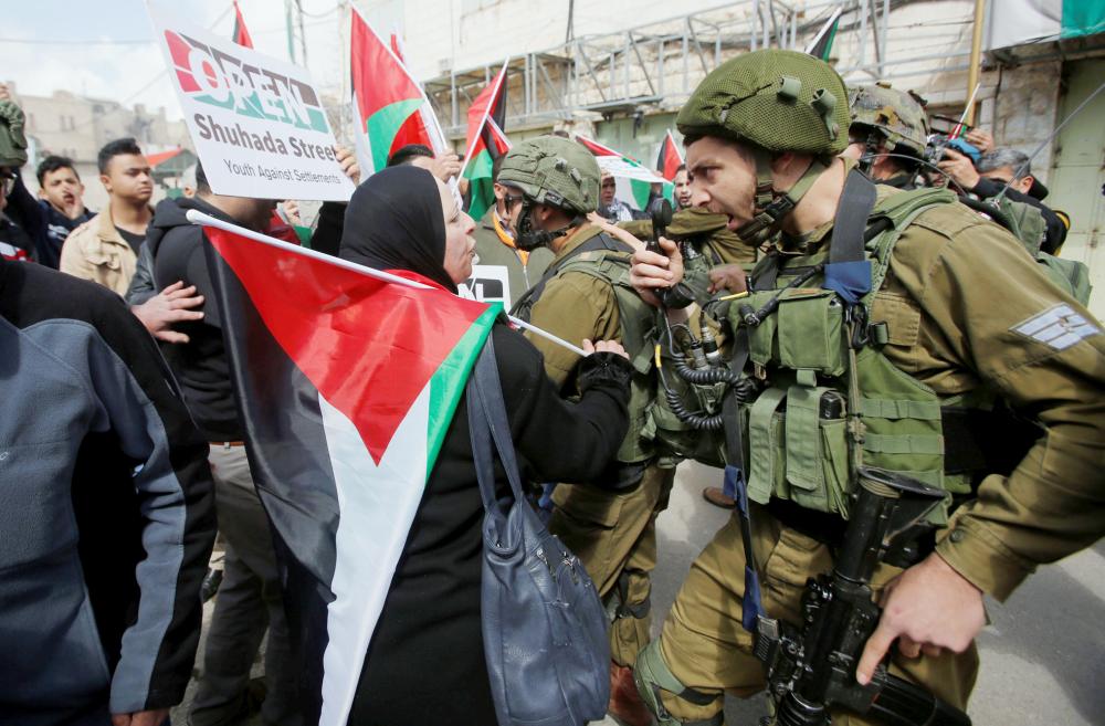 An Israeli soldier argues with a Palestinian demonstrator during clashes at a protest in Hebron, in the occupied West Bank February 23, 2018. REUTERS/Mussa Qawasma