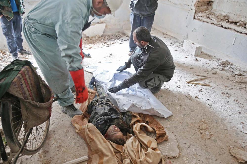 EDITORS NOTE: Graphic content / Syrian civil defence volunteers prepare to wrap the body of a victim who died in a building collapse following reported regime bombardment in Haza, in the besieged Eastern Ghouta region on the outskirts of the capital Damascus on February 26, 2018.  / AFP / ABDULMONAM EASSA
