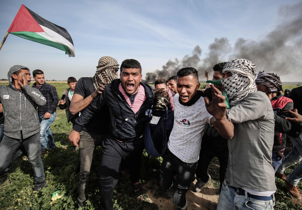 Palestinians help evacuate an injured protester during clashes with Israeli troops near Khan Yunis. — AFP