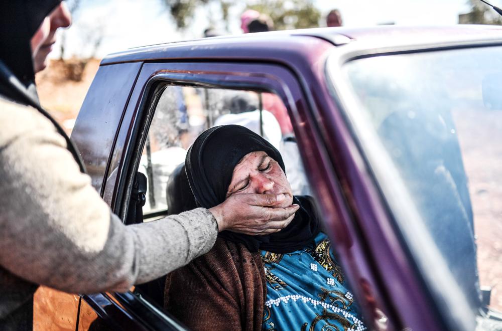 A woman sits in a car as people arrive at a check point in the village of Anab ahead of crossing to the Turkish-backed Syrian rebels side on March 17, 2018, as civilians flee the city of Afrin in northern Syria. More than 200,000 civilians have fled the city of Afrin in northern Syria in less than three days to escape a Turkish-led military offensive against a Kurdish militia, a war monitor said on March 17. Turkey and its Syrian Arab rebel allies have waged a nearly two-month offensive on the Afrin enclave, which is held by the Kurdish People's Protection Units (YPG). / AFP / BULENT KILIC
