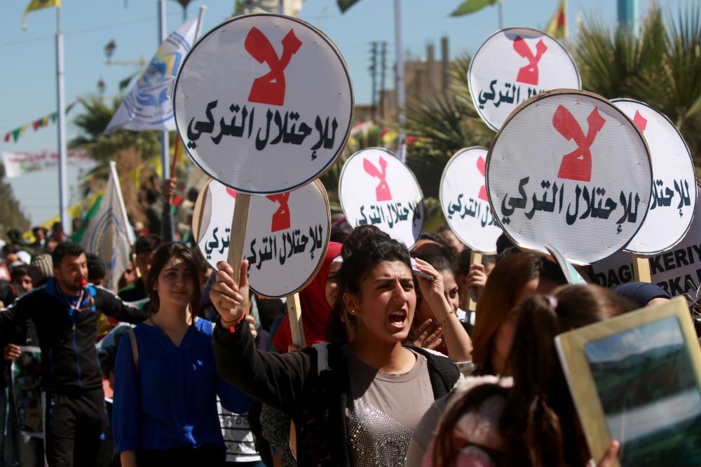 Syrian Kurds hold placards reading 