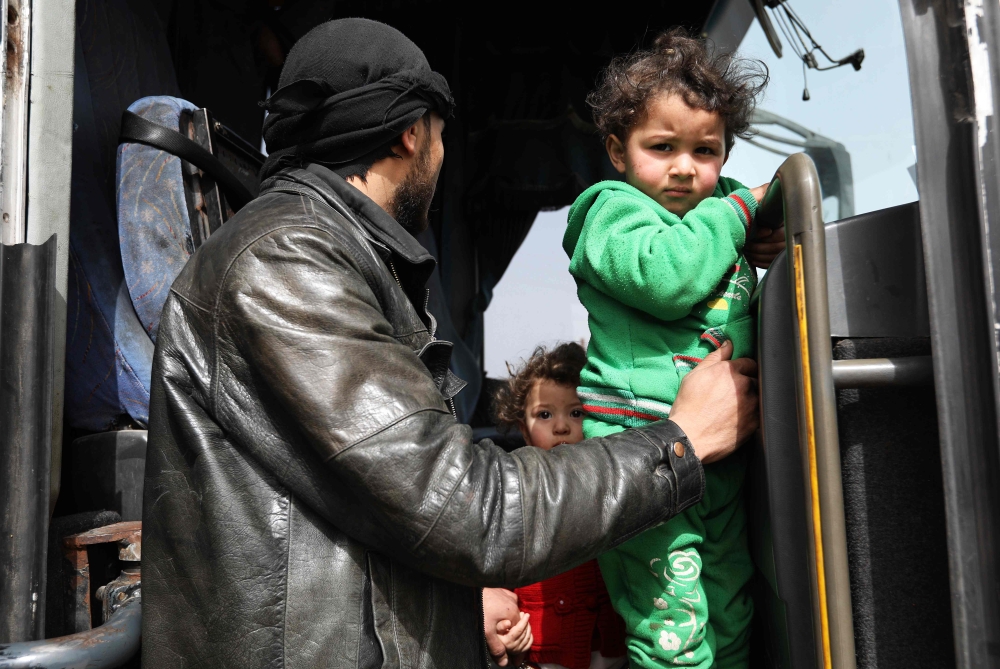 Syrians who were evacuated from the rebel-held town of Harasta in Eastern Ghouta arrive at a camp for displaced people in Maaret al-Ikhwan, in Syria's rebel-held Idlib province on March 23, 2018. Hundreds of fighters evacuated by the Syrian regime from their Eastern Ghouta bastion arrived in Idlib province, the Britain-based Syrian Observatory for Human Rights said. / AFP / OMAR HAJ KADOUR
