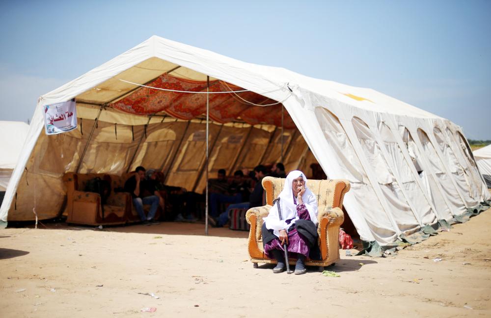 



مسنة فلسطينية تجلس أمام خيمة قرب الحدود بين إسرائيل وغزة خلال مظاهرة أمس. ( رويترز)