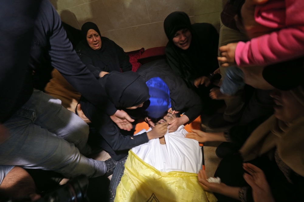 TOPSHOT - Palestinian mourners kiss the body of Thaer Rabaa, who died from his injuries after being shot by Israeli forces during clashes on the Israel-Gaza border, during his funeral in the Jabalia refugee camp, northern Gaza Strip on April 6 2018. Clashes erupted on the Gaza-Israel border on April 6, AFP journalists said, a week after similar demonstrations led to violence in which Israeli force killed 19 Palestinians, the bloodiest day since a 2014 war.
 / AFP / MOHAMMED ABED
