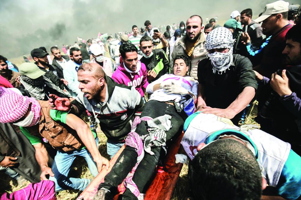 An injured Palestinian protestor is carried by fellow demonstrators during clashes with Israeli security forces following a demonstration calling for the right to return -- meaning Palestinian refugees being allowed to go back to the land they fled or were expelled from during the 1948 war surrounding Israel's creation -- near the border with Israel, east of Khan Yunis, in the southern Gaza Strip, on April 6, 2018 Clashes erupted on the Gaza-Israel border a week after similar demonstrations led to violence in which Israeli force killed 19 Palestinians, the bloodiest day since a 2014 war. / AFP / SAID KHATIB
