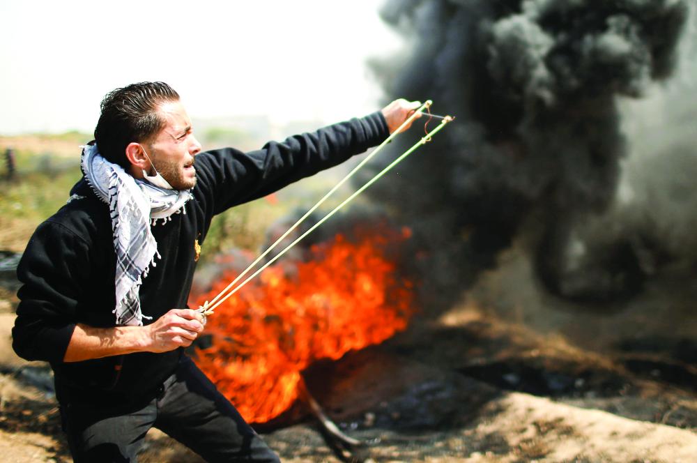 A Palestinian demonstrator hurls stones at Israeli troops during clashes at a protest demanding the right to return to their homeland, at the Israel-Gaza border east of Gaza City April 6, 2018. REUTERS/Mohammed Salem