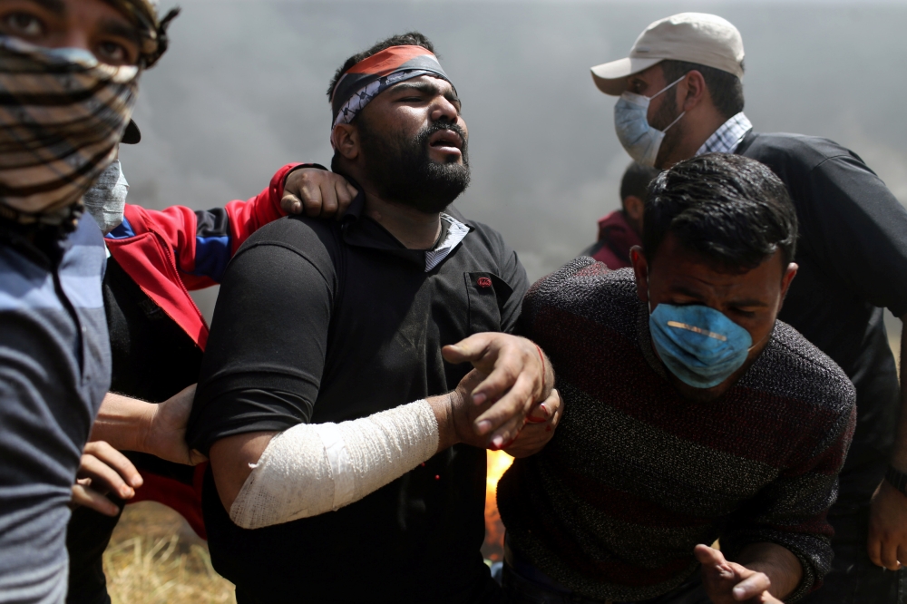 ATTENTION EDITORS - VISUAL COVERAGE OF SCENES OF INJURY OR DEATH A wounded Palestinian demonstrator is helped during clashes with Israeli troops at the Israel-Gaza border at a protest demanding the right to return to their homeland, in the southern Gaza Strip April 6, 2018. REUTERS/Ibraheem Abu Mustafa