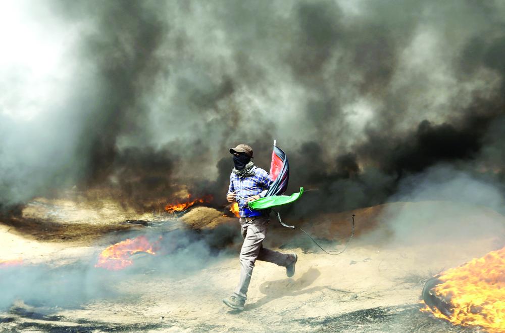 A demonstrator runs during clashes with Israeli troops at a protest where Palestinians demand the right to return to their homeland, at the Israel-Gaza border in the southern Gaza Strip, April 20, 2018. REUTERS/Ibraheem Abu Mustafa TPX IMAGES OF THE DAY