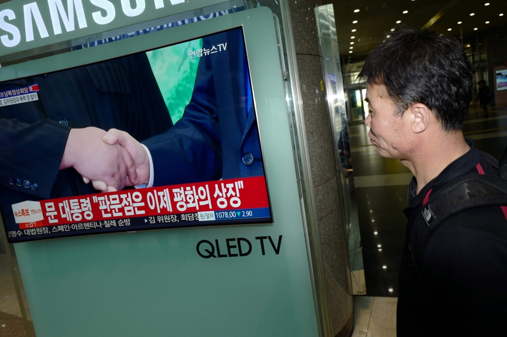 A public screen shows news coverage of South Korea's President Moon Jae-in and North Korean leader Kim Jong Un shaking hands during their inter-Korean summit meeting, at a railway station in Seoul on April 27, 2018. The leader of nuclear-armed North Korea Kim Jong Un and the South's President Moon Jae-in said they were committed to the denuclearisation of the Korean peninsula after a historic summit on April 27.
 / AFP / Argus Paul ESTABROOK
