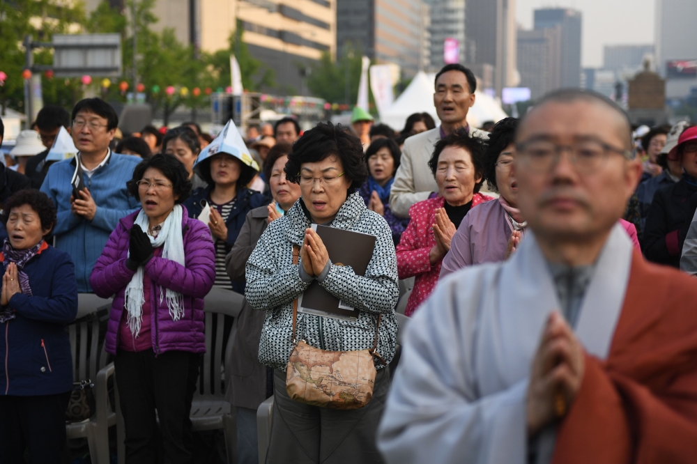 Buddhist followers pray for the success of the inter-Korean summit, in Seoul on April 27, 2018. The leader of nuclear-armed North Korea Kim Jong Un and the South's President Moon Jae-in said they were committed to the denuclearisation of the Korean peninsula after a historic summit on April 27. / AFP / GREG BAKER
