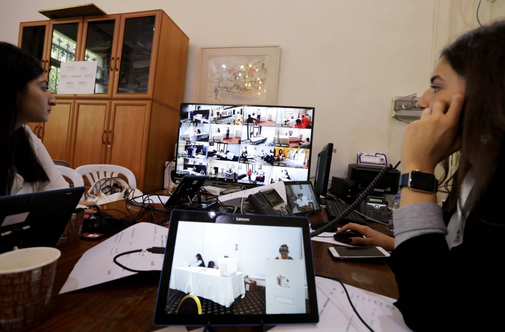 Members of Lebanon's electoral commission monitor screens bearing images of embassies around the Middle East at the Ministry of Foreign Affairs in Beirut to check the electoral process as Lebanese expats start voting in the Lebanese parliamentary elections on April 27, 2018. The 12,611 Lebanese voters registered in the Middle East will be the first to cast ballots for the 128 seats in Lebanon's parliament. / AFP / ANWAR AMRO
