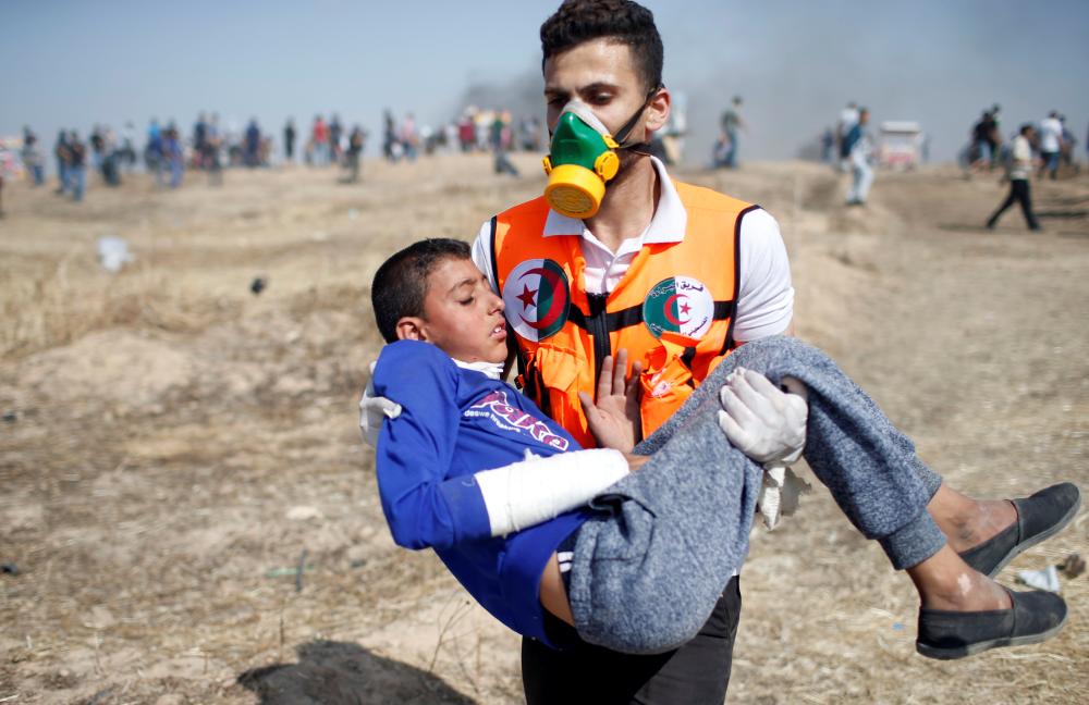 



إجلاء صبي فلسطيني أصيب خلال احتجاجات مطالب الفلسطينيين بحق الأرض، أمس الجمعة. (رويترز) 