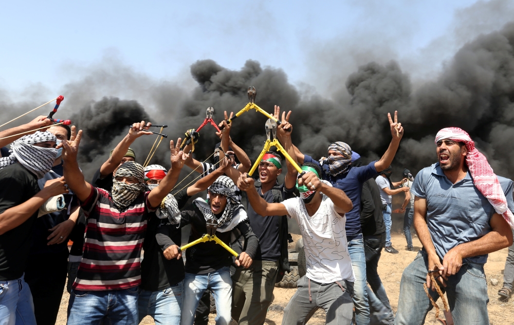 Palestinian demonstrators gesture as they hold wire cutters during a protest demanding the right to return to their homeland, at the Israel-Gaza border in the southern Gaza Strip, May 11, 2018. REUTERS/Ibraheem Abu Mustafa