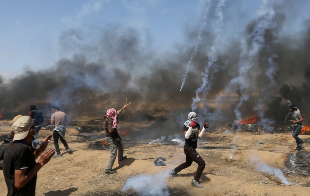 Tear gas canisters are fired by Israeli forces at Palestinian demonstrators during a protest demanding the right to return to their homeland, at the Israel-Gaza border in the southern Gaza Strip, May 11, 2018. REUTERS/Ibraheem Abu Mustafa