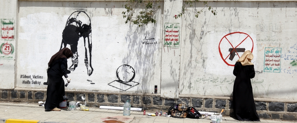 epa06725903 Yemeni artists Haifa Subay (L) and Sabreen Mahjali paint anti-child recruitment graffiti on a wall in Sana'a, Yemen, 10 May 2018. According to UNICEF, at least 2,369 cases of child recruitment and use of children in the conflict in Yemen have been verified since the Saudi-led coalition started a military campaign against the Houthi rebels in the impoverished Arab country in March 2015.  EPA/YAHYA ARHAB