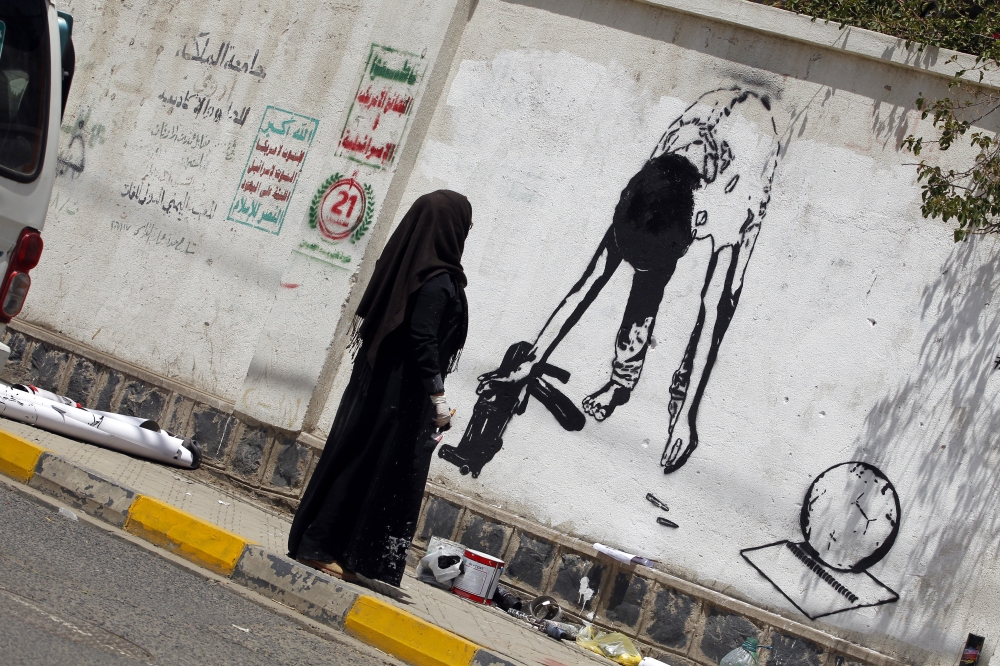 epa06725901 Yemeni artist Haifa Subay paints an anti-child recruitment graffiti on a wall in Sana'a, Yemen, 10 May 2018. According to UNICEF, at least 2,369 cases of child recruitment and use of children in the conflict in Yemen have been verified since the Saudi-led coalition started a military campaign against the Houthi rebels in the impoverished Arab country in March 2015.  EPA/YAHYA ARHAB