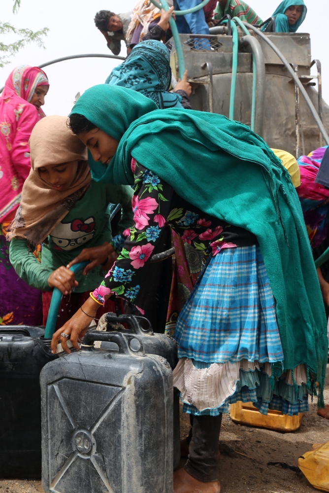 Yemenis gather next to a water tank to collect water in an impoverished coastal village on the outskirts of the Yemeni port city of Hodeidah, on May 12, 2018.  / AFP / ABDO HYDER
