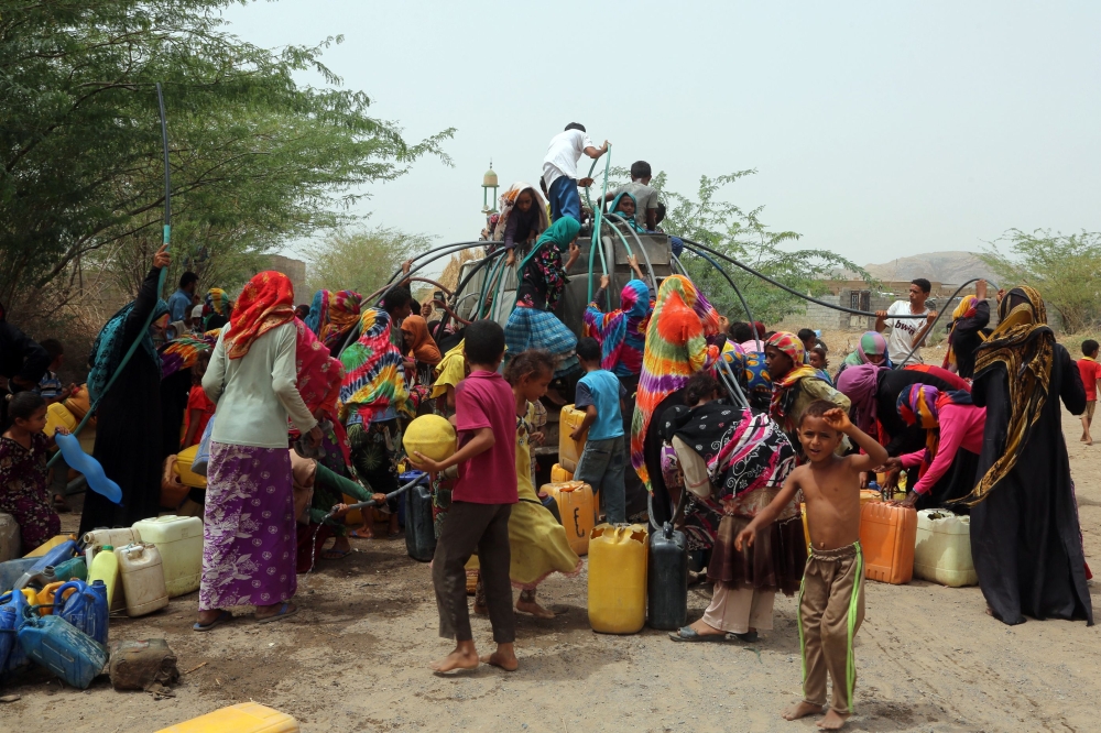 Yemenis gather next to a water tank to collect water in an impoverished coastal village on the outskirts of the Yemeni port city of Hodeidah, on May 12, 2018.  / AFP / ABDO HYDER
