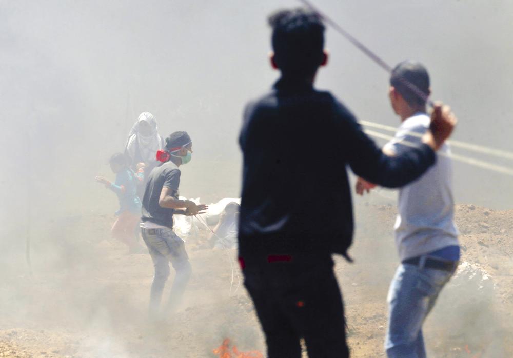 Palestinian children use slingshots during clashes with Israeli forces near the border between Israel and the Gaza strip, east of Jabalia on May 14, 2018, as Palestinians  protest over the inauguration of the US embassy following its controversial move to Jerusalem.  / AFP / MOHAMMED ABED
