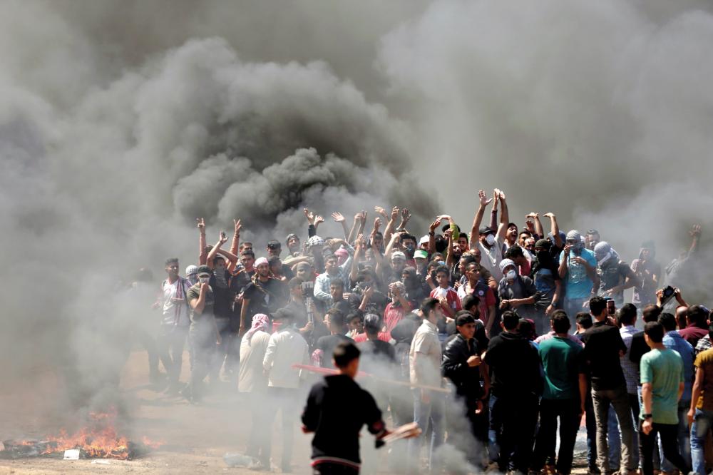 CORRECTION / Palestinian demonstrators burn tyres near the Gaza-Israel border, east of Gaza City, as Palestinians readied for protests over the inauguration of the US embassy following its controversial move to Jerusalem on May 14, 0218.   / AFP / MAHMUD HAMS
