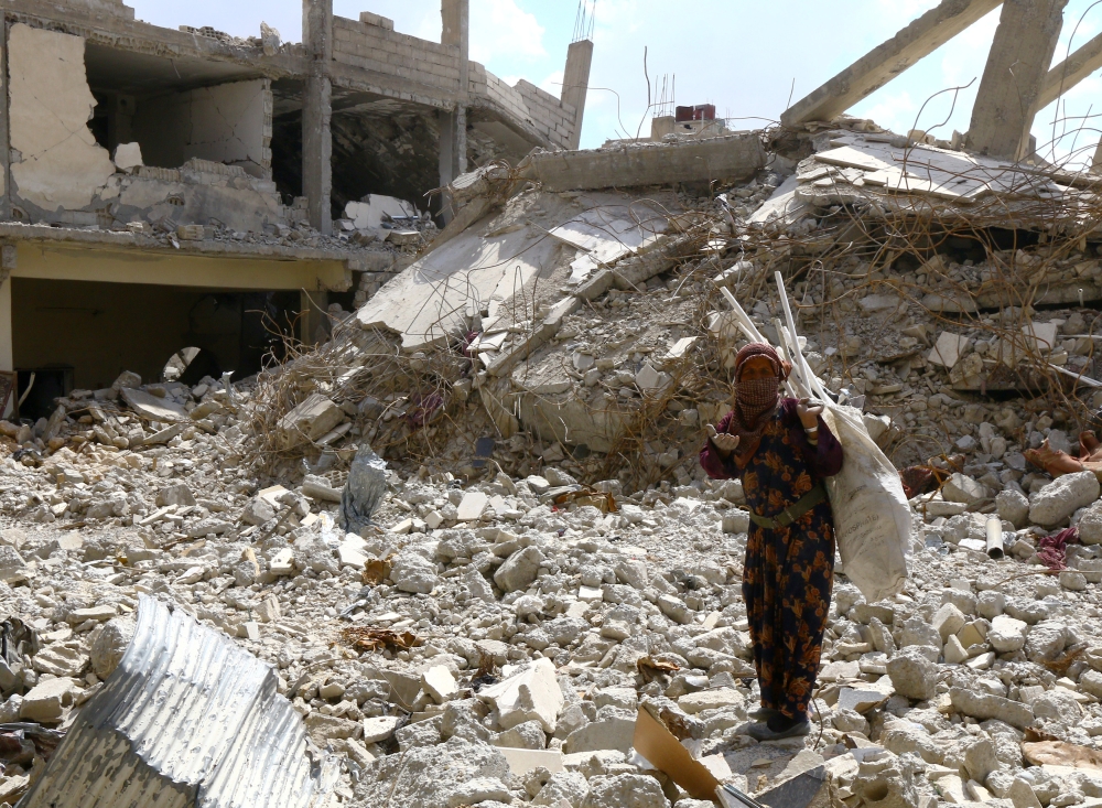 A woman gestures as she stands on rubble of damaged buildings in Raqqa, Syria May 14, 2018. REUTERS/Aboud Hamam