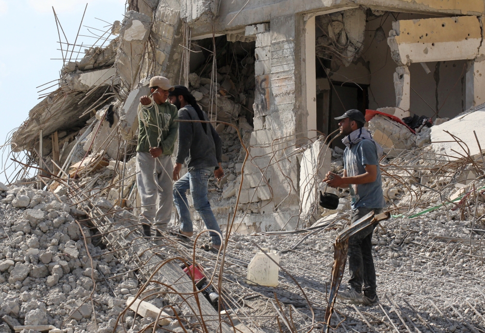 A worker holds a teapot as he walks on rubble of damaged buildings in Raqqa, Syria May 14, 2018. REUTERS/Aboud Hamam