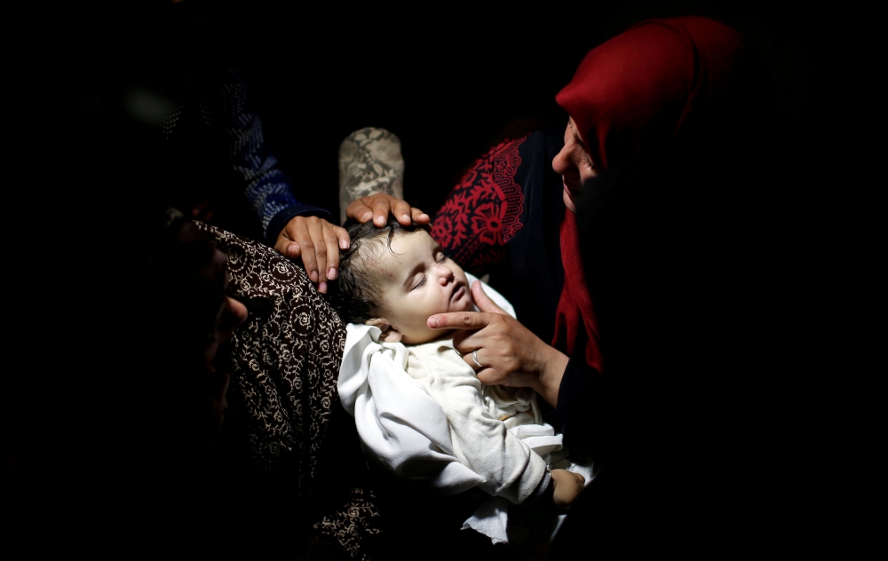 ATTENTION EDITORS - VISUAL COVERAGE OF SCENES OF INJURY OR DEATH A relative mourns as she carries the body of eight-month-old Palestinian infant Laila al-Ghandour, who died after inhaling tear gas during a protest against U.S embassy move to Jerusalem at the Israel-Gaza border, during her funeral in Gaza City May 15, 2018. REUTERS/Mohammed Salem TEMPLATE OUT TPX IMAGES OF THE DAY