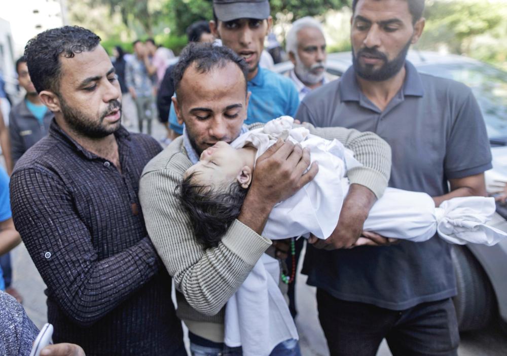 The father of a Leila al-Ghandour (C), a Palestinian baby of 8 months who according to the Palestinian health ministry died of tear gas inhalation during clashes in East Gaza the previous day, mourns her in front of the morgue of al-Shifa hospital in Gaza City on May 15, 2018 Fresh protests are expected a day after Israeli forces killed 59 Palestinians during clashes and protests along the Gaza border against the US embassy opening in Jerusalem in the conflict's bloodiest day in years. / AFP / MAHMUD HAMS
