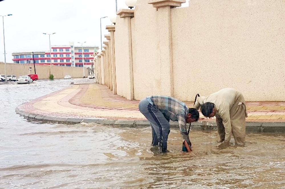 



عاملا نظافة أثناء موسم الأمطار.