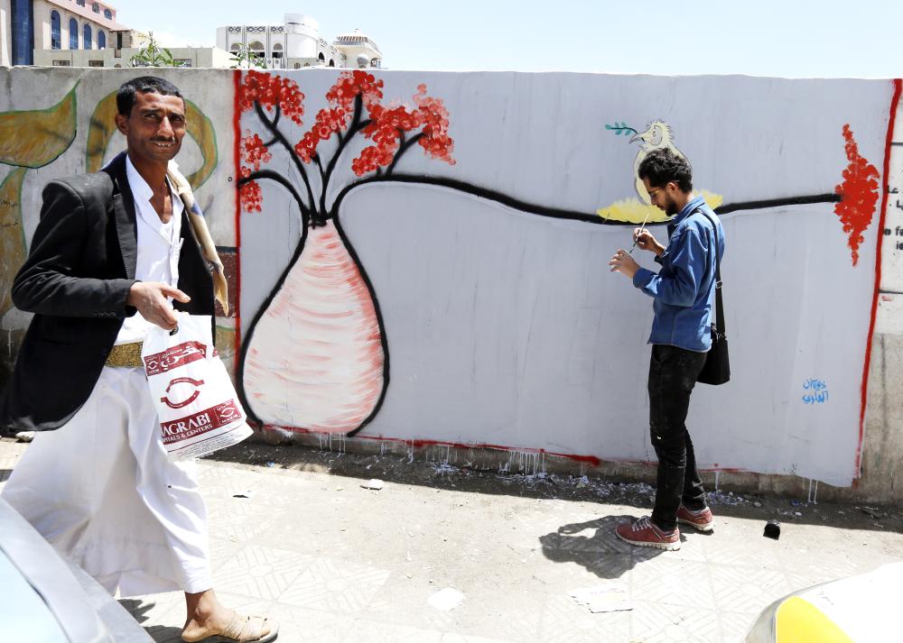 epa06776808 A Yemeni walks past an artist working on a graffiti of a bottle tree, an endemic tree of Socotra Island, on a wall in Sana'a, Yemen, 31 May 2018 (issued 01 June 2018). Socotra Island, located in the Indian Ocean around 250 miles off the coast of Yemen, was listed as a world natural heritage site by United Nations Educational, Scientific and Cultural Organization (UNESCO) in July 2008. Socotra is teeming with 825 rare species of plants of which more than a third are endemic.  EPA/YAHYA ARHAB