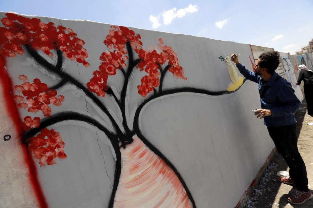 epa06776810 A Yemeni artist works on a graffiti of a bottle tree, an endemic tree of Socotra Island, on a wall in Sana'a, Yemen, 31 May 2018 (issued 01 June 2018). Socotra Island, located in the Indian Ocean around 250 miles off the coast of Yemen, was listed as a world natural heritage site by United Nations Educational, Scientific and Cultural Organization (UNESCO) in July 2008. Socotra is teeming with 825 rare species of plants of which more than a third are endemic.  EPA/YAHYA ARHAB