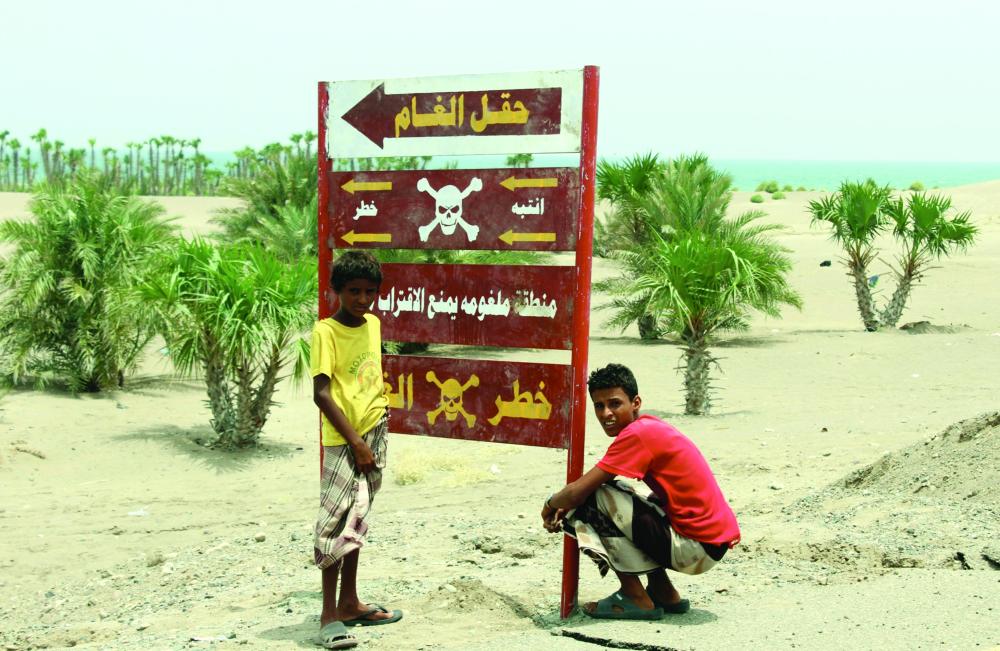 



فتيان يمنيان يقفان أمام إشارة تحذر الناس من الاقتراب من حقل ألغام على طريق يؤدي إلى بلدة الخوخة، أمس الأول. (أ.ف.ب)