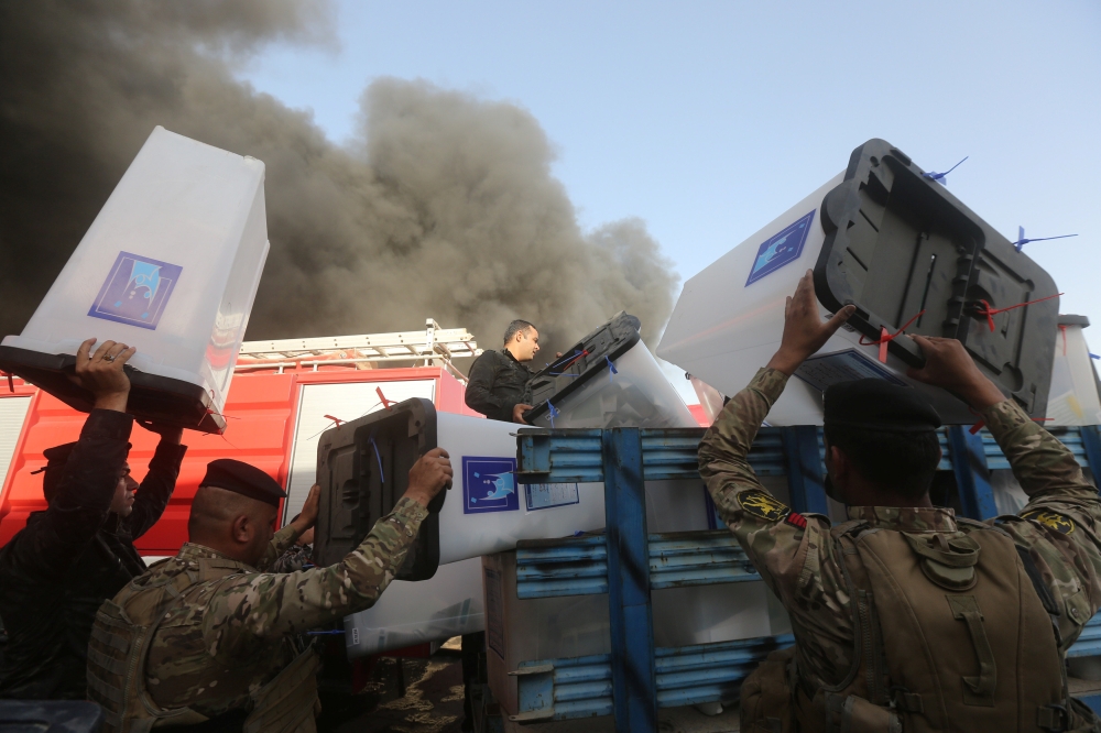 Security forces carry ballot boxes as smoke rises from a storage site in Baghdad, housing the boxes from Iraq's May parliamentary election, Iraq June 10, 2018. REUTERS/Stringer NO RESALES. NO ARCHIVES