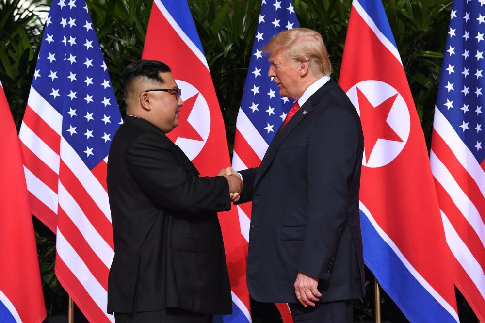 North Korea's leader Kim Jong Un (L) shakes hands with US President Donald Trump (R) at the start of their historic US-North Korea summit, at the Capella Hotel on Sentosa island in Singapore on June 12, 2018. Donald Trump and Kim Jong Un have become on June 12 the first sitting US and North Korean leaders to meet, shake hands and negotiate to end a decades-old nuclear stand-off. / AFP / SAUL LOEB
