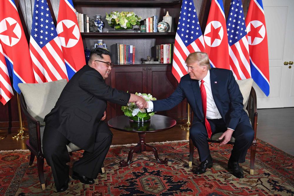 US President Donald Trump (R) shakes hands with North Korea's leader Kim Jong Un (L) as they sit down for their historic US-North Korea summit, at the Capella Hotel on Sentosa island in Singapore on June 12, 2018. Donald Trump and Kim Jong Un have become on June 12 the first sitting US and North Korean leaders to meet, shake hands and negotiate to end a decades-old nuclear stand-off. / AFP / SAUL LOEB
