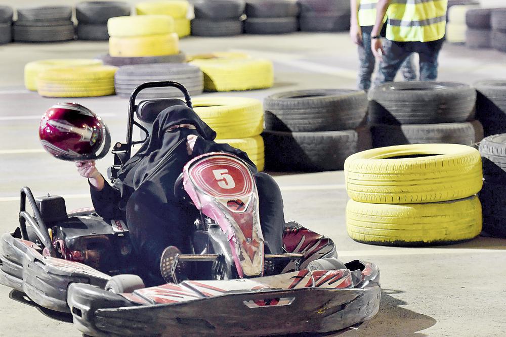 A Saudi woman prepares to wear a helmet for a test drive using a go-cart during a driving workshop for women in the Saudi capital Riyadh on June 21, 2018. Saudi Arabia will allow women to drive from June 24, ending the world's only ban on female motorists, a historic reform marred by what rights groups call an expanding crackdown on activists. / AFP / FAYEZ NURELDINE
