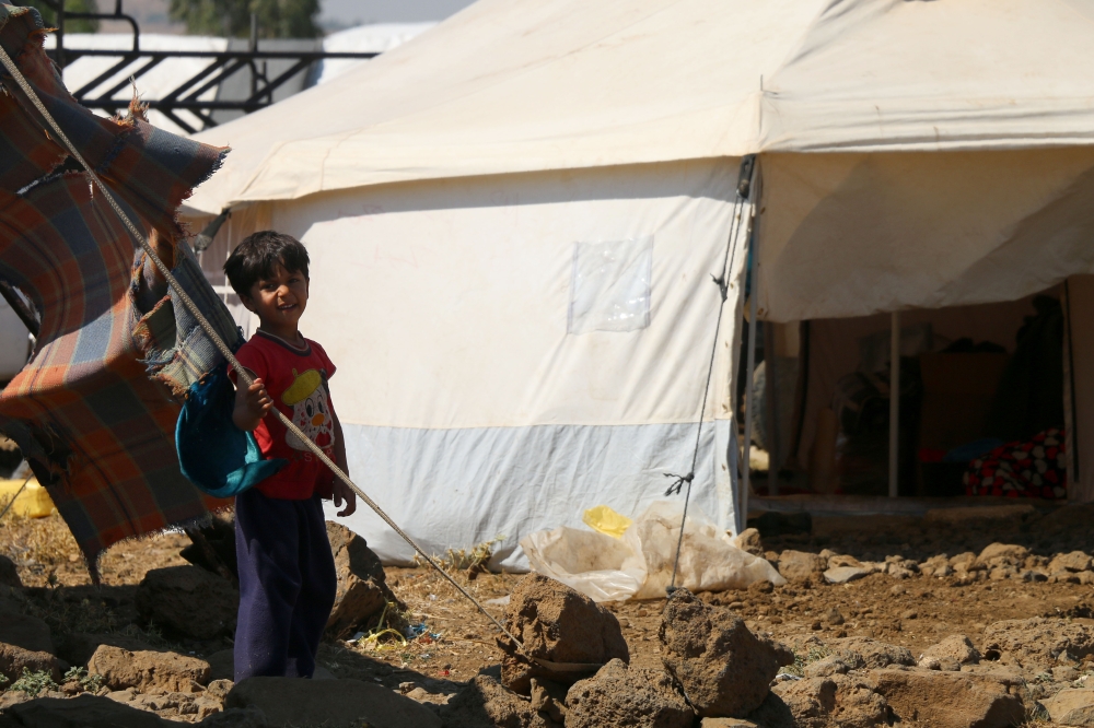 A displaced Syrian child from the province of Daraa smiles at a makeshift camp in the village of al-Rafid in the border area between the Israeli-occupied Golan heights and Syria on June 27, 2018. / AFP / Ahmad al-Msalam 