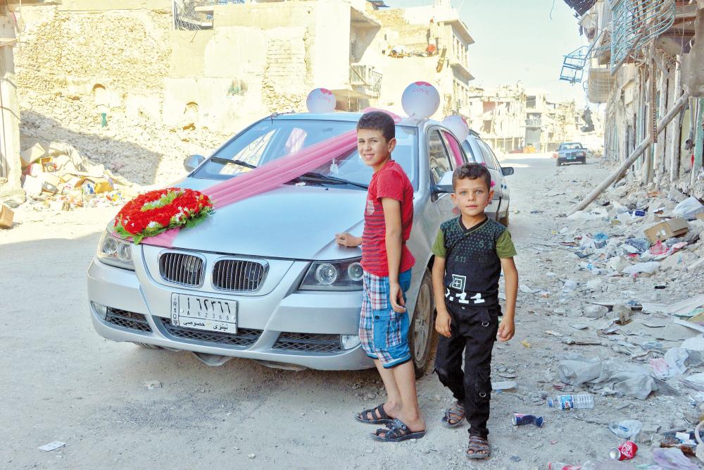 Iraqi children stand next to a car that has been decorated for the first wedding in the old city of Mosul a year after the city was retaken by the Iraqi government forces, on July 9, 2018. Iraqi forces announced the «liberation» of the country's second city on July 10, 2017, after a bloody nine-month offencive to end the Islamic State (IS) group's three-year rule there. Scores of people are still displaced in and around Mosul as the city lies in ruins, one year after it was retaken from IS. / AFP / Zaid AL-OBEIDI
