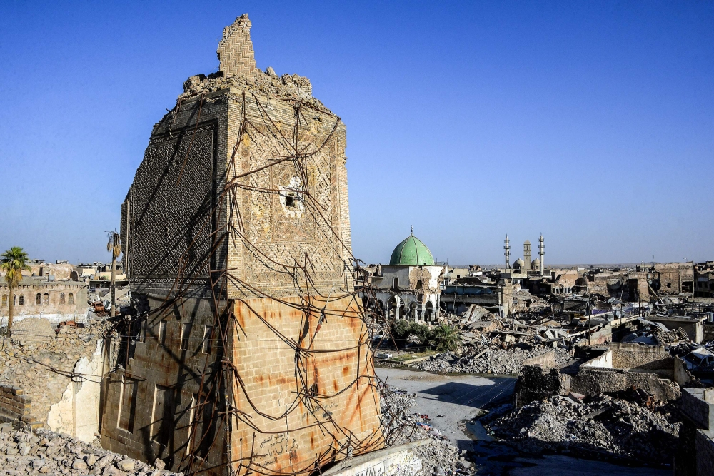 TOPSHOT - A picture taken on July 9, 2018 shows a view of the base of the destroyed «Al-Hadba» leaning minaret, with the dome of the destroyed Al-Nuri Mosque seen behind in the Old City of Mosul, a year after the city was retaken by the Iraqi government forces. Iraqi forces announced the «liberation» of the country's second city on July 10, 2017, after a bloody nine-month offencive to end the Islamic State (IS) group's three-year rule there. Scores of people are still displaced in and around Mosul as the city lies in ruins, one year after it was retaken from IS. / AFP / Zaid AL-OBEIDI
