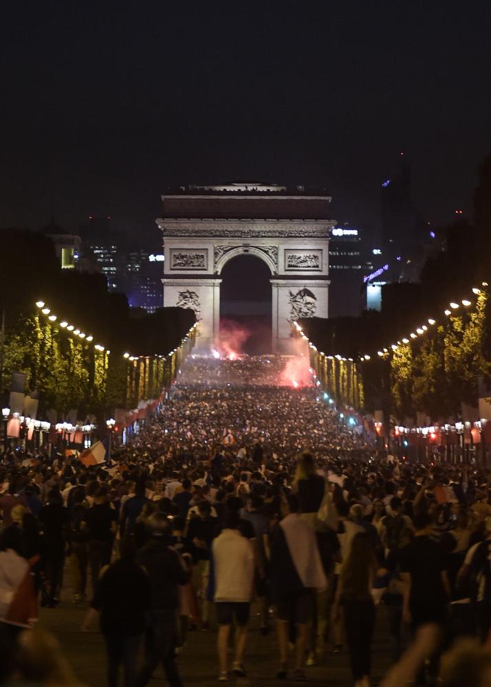 People celebrate France's victory in front of The Arc de Triomphe on the Champs Elysees in Paris on July 10, 2018, after the final whistle of the Russia 2018 World Cup semi-final football match between France and Belgium. / AFP / Lucas BARIOULET
