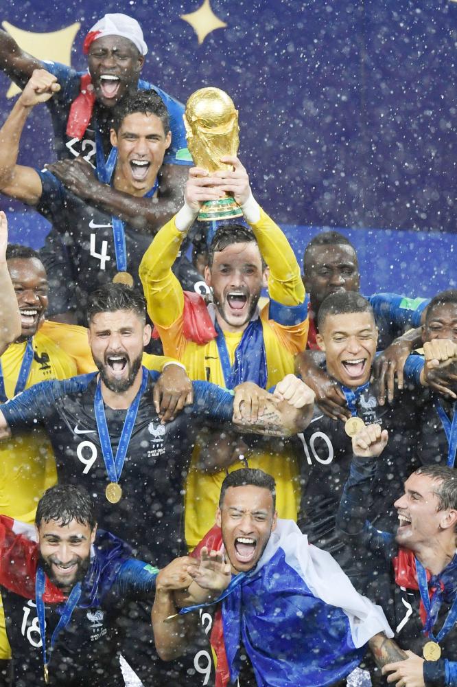 France's goalkeeper Hugo Lloris (C) holds the trophy next to France's forward Olivier Giroud (R) and France's forward Kylian Mbappe (L) as they celebrate with teammates during the trophy ceremony after winning the Russia 2018 World Cup final football match between France and Croatia at the Luzhniki Stadium in Moscow on July 15, 2018. RESTRICTED TO EDITORIAL USE - NO MOBILE PUSH ALERTS/DOWNLOADS

 / AFP / GABRIEL BOUYS / RESTRICTED TO EDITORIAL USE - NO MOBILE PUSH ALERTS/DOWNLOADS

