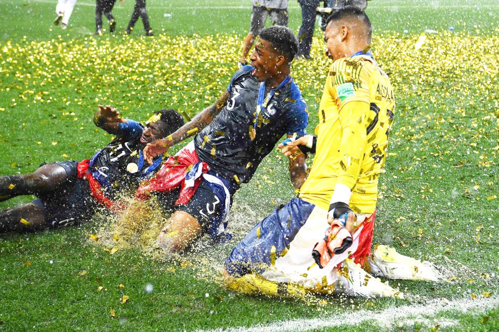 (L to R) France's forward Ousmane Dembele, France's defender Presnel Kimpembe and France's goalkeeper Alphonse Areola celebrate after winning the Russia 2018 World Cup final football match between France and Croatia at the Luzhniki Stadium in Moscow on July 15, 2018. RESTRICTED TO EDITORIAL USE - NO MOBILE PUSH ALERTS/DOWNLOADS

 / AFP / FRANCK FIFE / RESTRICTED TO EDITORIAL USE - NO MOBILE PUSH ALERTS/DOWNLOADS

