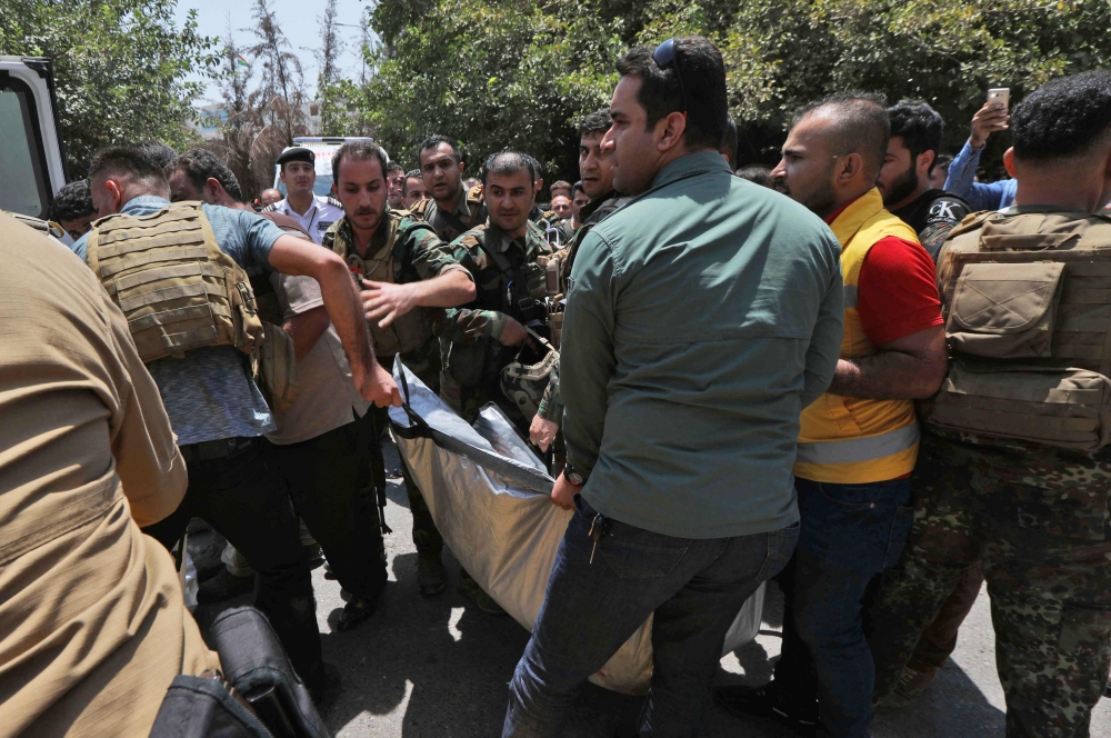 Kurdish security forces carry the body of a killed gunman in front of the Erbil governorate headquarters after an attack in Erbil, the capital of autonomous Iraqi Kurdistan on July 23, 2018. An official was killed on July 23 at the headquarters of the governorate of Erbil, capital of Iraqi Kurdistan, during an attack by three gunmen later shot dead by security forces, officials said. / AFP / SAFIN HAMED 