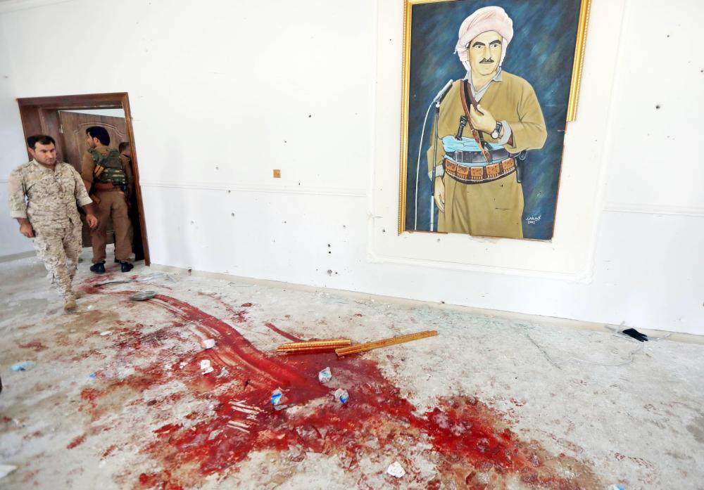 An official stands by blood strains at the Erbil governorate headquarters after an attack in Erbil, the capital of autonomous Iraqi Kurdistan on July 23, 2018. An official was killed on July 23 at the headquarters of the governorate of Erbil, capital of Iraqi Kurdistan, during an attack by three gunmen later shot dead by security forces, officials said. / AFP / SAFIN HAMED 